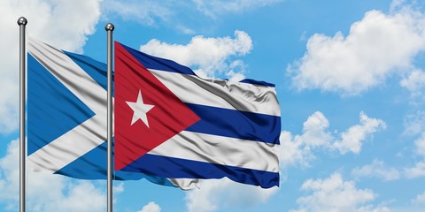 Scotland and Cuba flag waving in the wind against white cloudy blue sky together. Diplomacy concept, international relations.