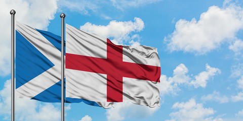 Scotland and England flag waving in the wind against white cloudy blue sky together. Diplomacy concept, international relations.