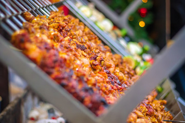 Selective focus, chicken kebabs cooking on a charcoal grill at Christmas market winter wonderland in London