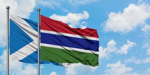 Scotland and Gambia flag waving in the wind against white cloudy blue sky together. Diplomacy concept, international relations.