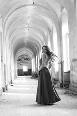 Naklejka premium Young beautiful short hair blonde woman in black climbing the stairs, black and white photo. Side view of elegant romantic mysterious lady with movie star look in interior with bricks walls