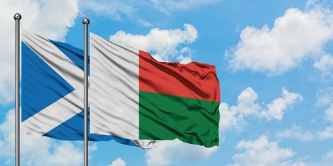 Scotland and Madagascar flag waving in the wind against white cloudy blue sky together. Diplomacy concept, international relations.