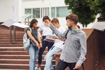 Positive guy. Group of young students in casual clothes near university at daytime