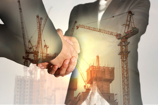 Double exposure of businesswomen double handshake, construction crane, bulilding and sunlight of sunset as business, commitment, congratulation, welcome and industry concept.