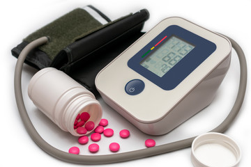 electronic blood pressure monitor with pills on a white background. Medical tonometer.