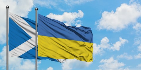 Scotland and Ukraine flag waving in the wind against white cloudy blue sky together. Diplomacy concept, international relations.