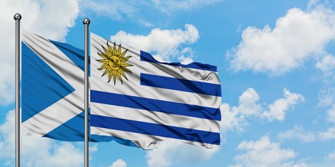 Scotland and Uruguay flag waving in the wind against white cloudy blue sky together. Diplomacy concept, international relations.