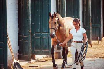 Getting ready for the ride. Horsewoman in white uniform with her horse at farm. Ready for the ride
