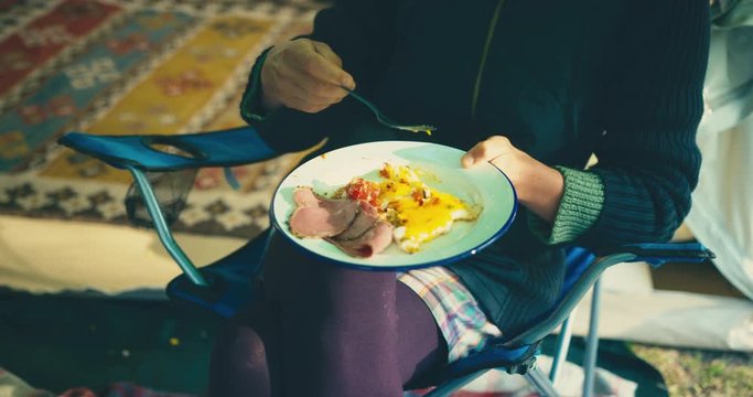 Young woman eating eggs in luxury tent
