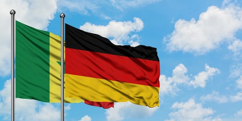 Senegal and Germany flag waving in the wind against white cloudy blue sky together. Diplomacy concept, international relations.
