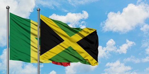 Senegal and Jamaica flag waving in the wind against white cloudy blue sky together. Diplomacy concept, international relations.