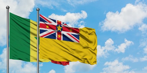 Senegal and Niue flag waving in the wind against white cloudy blue sky together. Diplomacy concept, international relations.