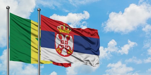 Senegal and Serbia flag waving in the wind against white cloudy blue sky together. Diplomacy concept, international relations.
