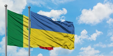 Senegal and Ukraine flag waving in the wind against white cloudy blue sky together. Diplomacy concept, international relations.