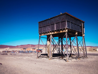 Fototapeta premium old water tank for steam trains, with blue sky in the train cemetery of uyuni, Bolivia