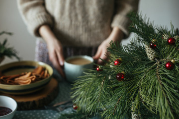 On Christmas morning a girl in a knitted jacket holding a hot mug of coffee