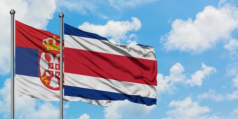 Serbia and Costa Rica flag waving in the wind against white cloudy blue sky together. Diplomacy concept, international relations.