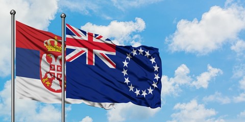 Serbia and Cook Islands flag waving in the wind against white cloudy blue sky together. Diplomacy concept, international relations.