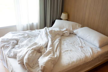 Messy bed. Couple pillows with white blanket on unmade  bed.