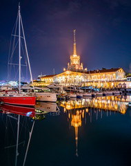 Marine Station of Sochi, illuminated with lights at night with reflection in water. Yachts and...