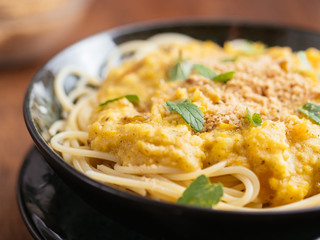 Bowl with spaghetti with a green tomato sauce and vegan walnut parmesan