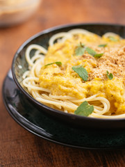 Bowl with spaghetti with a green tomato sauce and vegan walnut parmesan