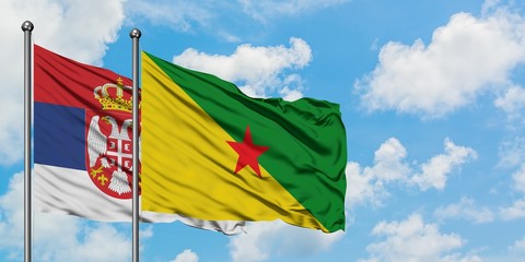 Serbia and French Guiana flag waving in the wind against white cloudy blue sky together. Diplomacy concept, international relations.