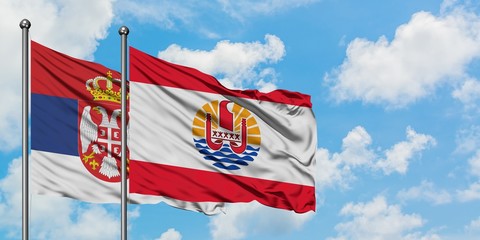 Serbia and French Polynesia flag waving in the wind against white cloudy blue sky together. Diplomacy concept, international relations.