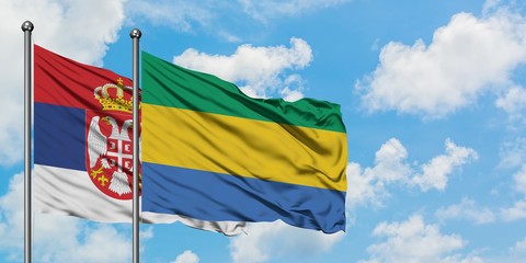 Serbia and Gabon flag waving in the wind against white cloudy blue sky together. Diplomacy concept, international relations.