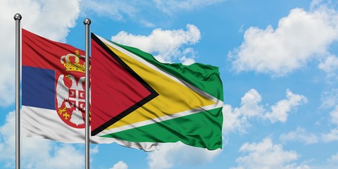 Serbia and Guyana flag waving in the wind against white cloudy blue sky together. Diplomacy concept, international relations.