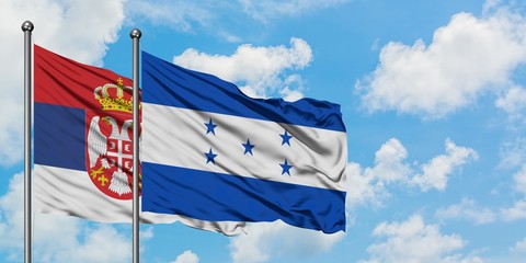 Serbia and Honduras flag waving in the wind against white cloudy blue sky together. Diplomacy concept, international relations.