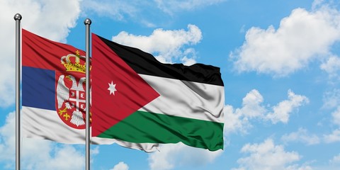 Serbia and Jordan flag waving in the wind against white cloudy blue sky together. Diplomacy concept, international relations.
