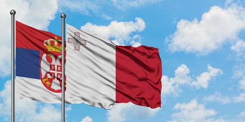 Serbia and Malta flag waving in the wind against white cloudy blue sky together. Diplomacy concept, international relations.