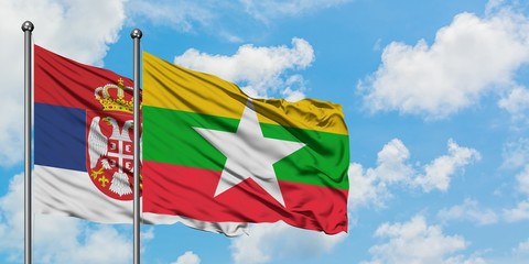 Serbia and Myanmar flag waving in the wind against white cloudy blue sky together. Diplomacy concept, international relations.