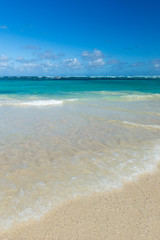 Fototapeta na wymiar Sea wave on the sand of a tropical beach in a wild turquoise bay