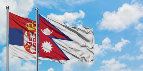 Serbia and Nepal flag waving in the wind against white cloudy blue sky together. Diplomacy concept, international relations.