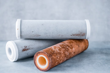 Old used cartridges for a water filter on a gray background.