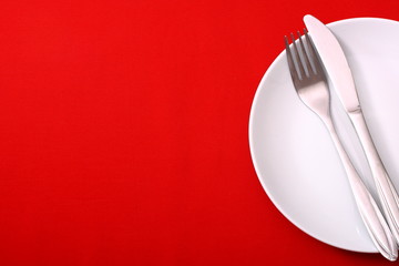 empty plate with fork and knife on red