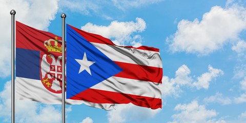 Serbia and Puerto Rico flag waving in the wind against white cloudy blue sky together. Diplomacy concept, international relations.