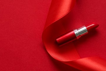 Luxury lipstick and silk ribbon on red holiday background, make-up and cosmetics flatlay for beauty...