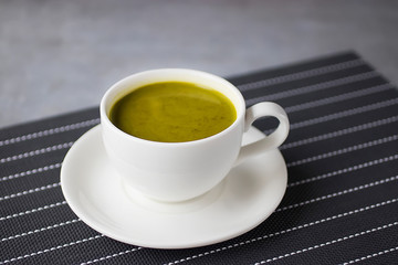 Matcha latte in a white cup on a gray background. Superfood concept.