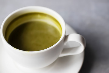 Matcha latte in a white cup on a gray background. Superfood concept.