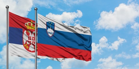 Serbia and Slovenia flag waving in the wind against white cloudy blue sky together. Diplomacy concept, international relations.