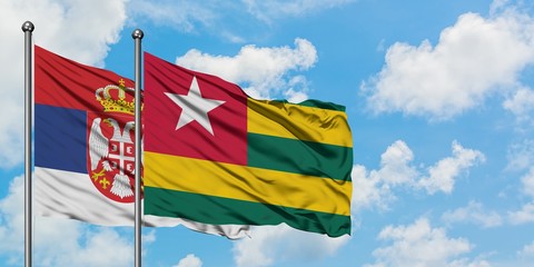 Serbia and Togo flag waving in the wind against white cloudy blue sky together. Diplomacy concept, international relations.