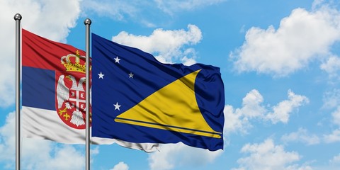 Serbia and Tokelau flag waving in the wind against white cloudy blue sky together. Diplomacy concept, international relations.