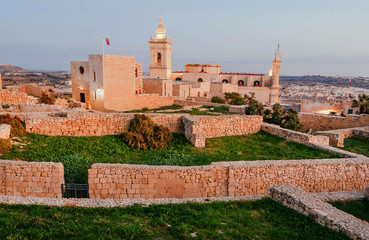 Fototapeta na wymiar Sunset hour over the Cittadella, 16th century fortification walls on Gozo island. historical Malta landscape