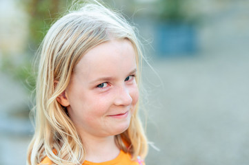 Close up headshot of a young, pretty blonde girl looking at the camera and trying not to laugh