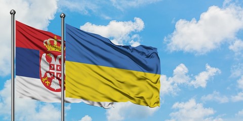 Serbia and Ukraine flag waving in the wind against white cloudy blue sky together. Diplomacy concept, international relations.