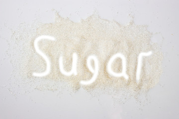 Sugar sprinkled on a white background with the words sugar.