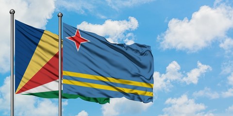 Seychelles and Aruba flag waving in the wind against white cloudy blue sky together. Diplomacy concept, international relations.
